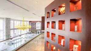 Un hall d’hôtel moderne avec une rambarde en verre, un lustre et un sol en marbre.