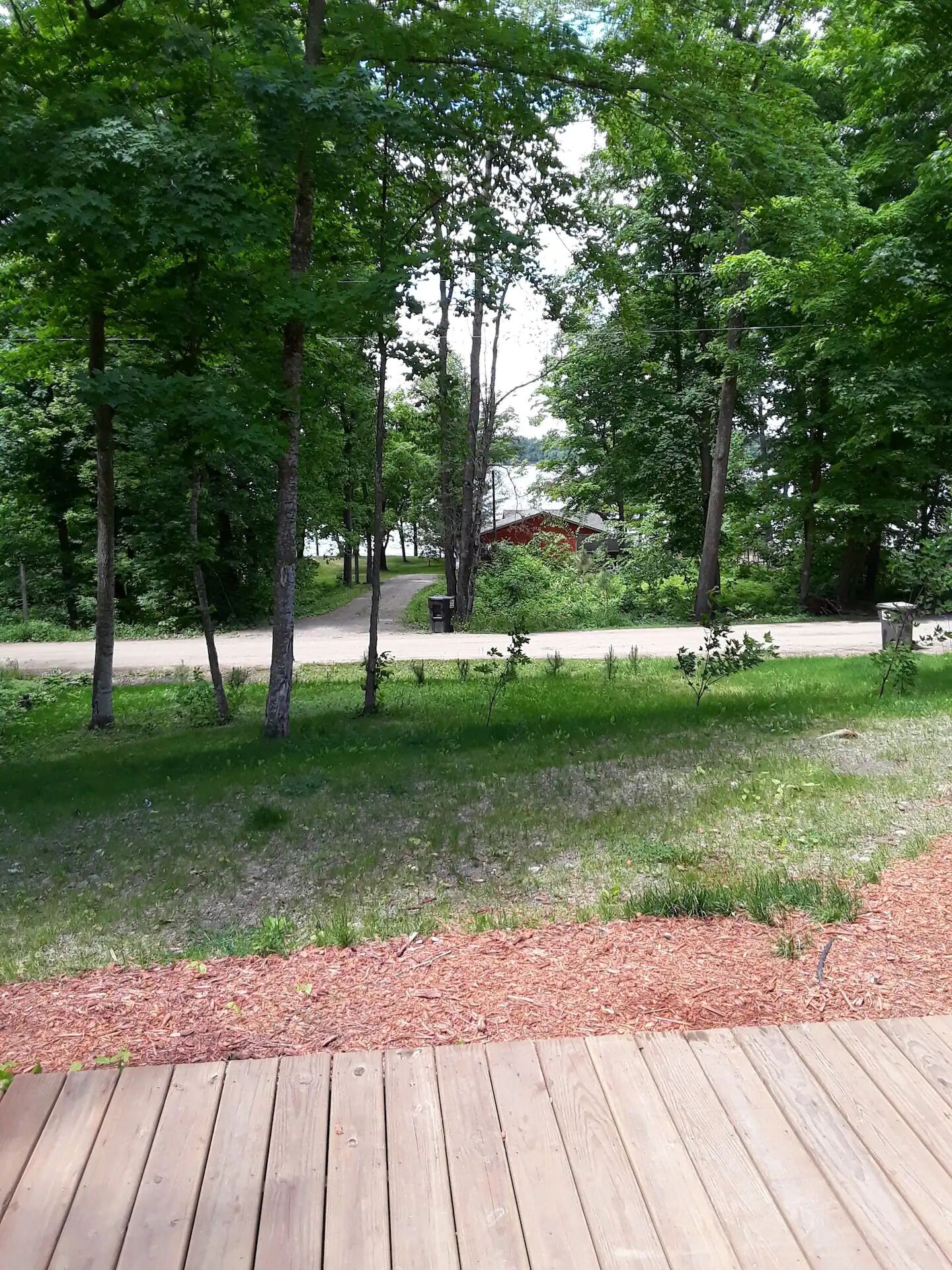 A wooden deck with a grassy area and trees.
