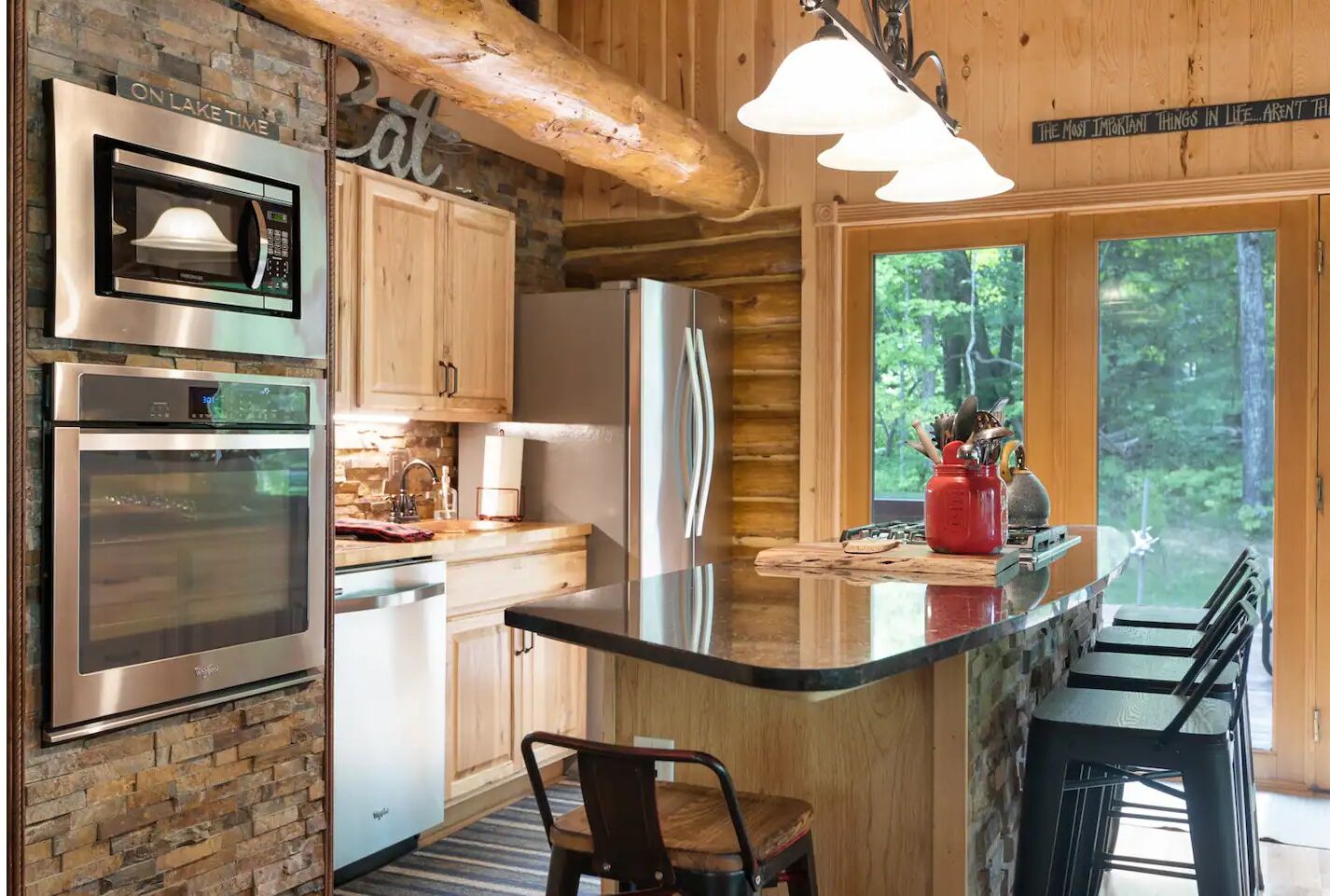 Una cocina moderna con electrodomésticos de acero inoxidable, armarios de madera y una isla grande con taburetes de bar.