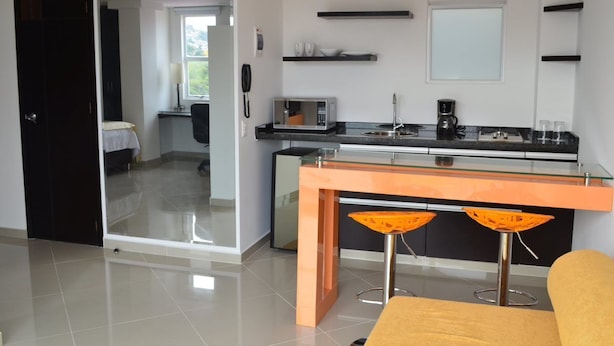 A modern kitchen with a glass-top island, two bar stools, a microwave, and a coffee maker. - A spacious and fabulous   387 ft2 studio, near every thing in Cali (Cali)