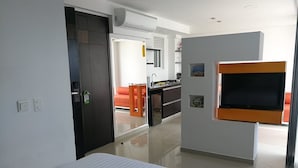 A modern hotel room with a bed, a TV mounted on the wall, a kitchen area, and a door leading to another room. - A spacious and fabulous   387 ft2 studio, near every thing in Cali (Cali)