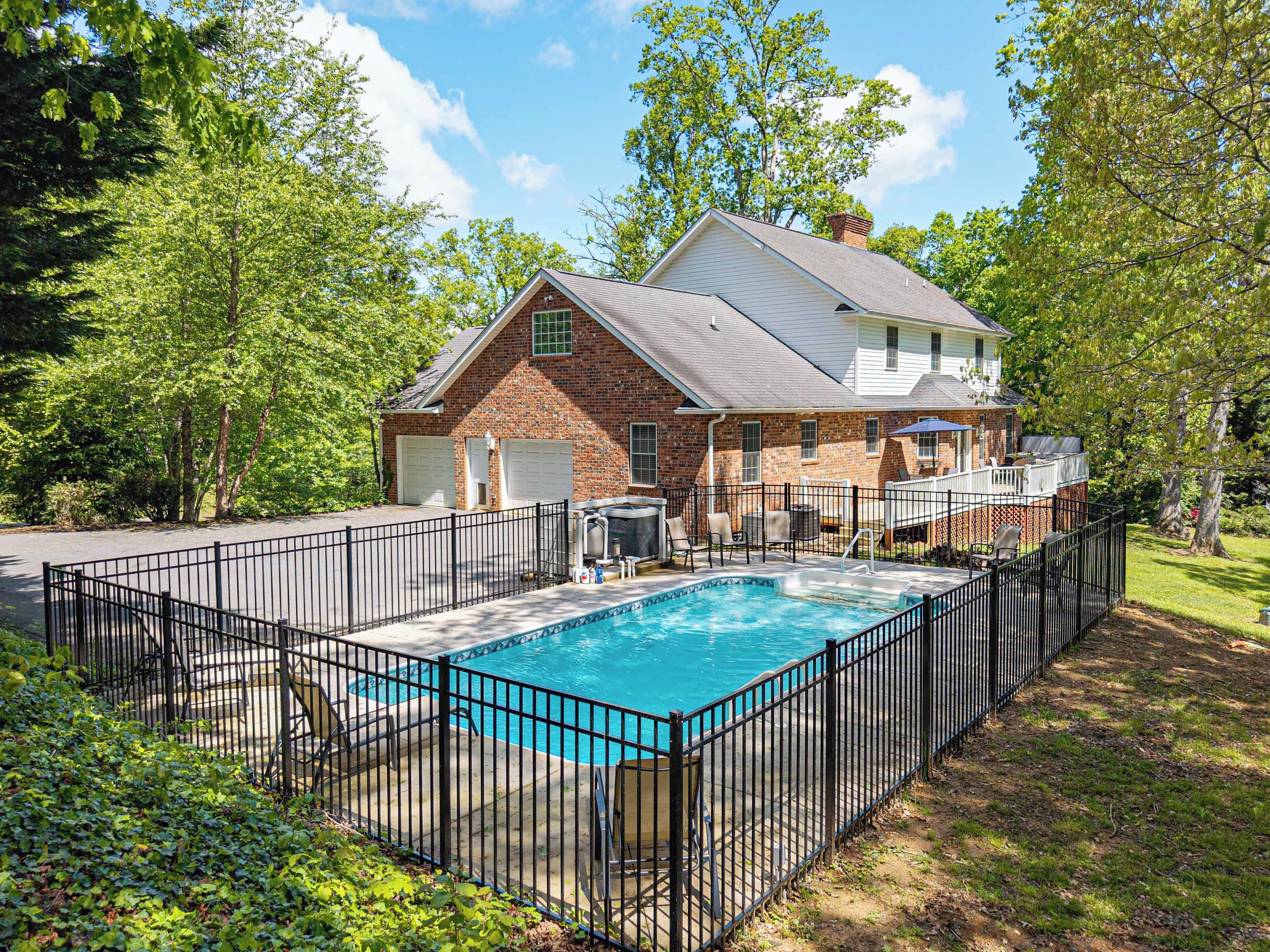 Ein zweigeschossiges Haus mit Schwimmbad, umgeben von einem schwarzen Metallzaun.
