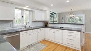 A modern kitchen with white cabinets, a granite countertop, and a wooden floor.