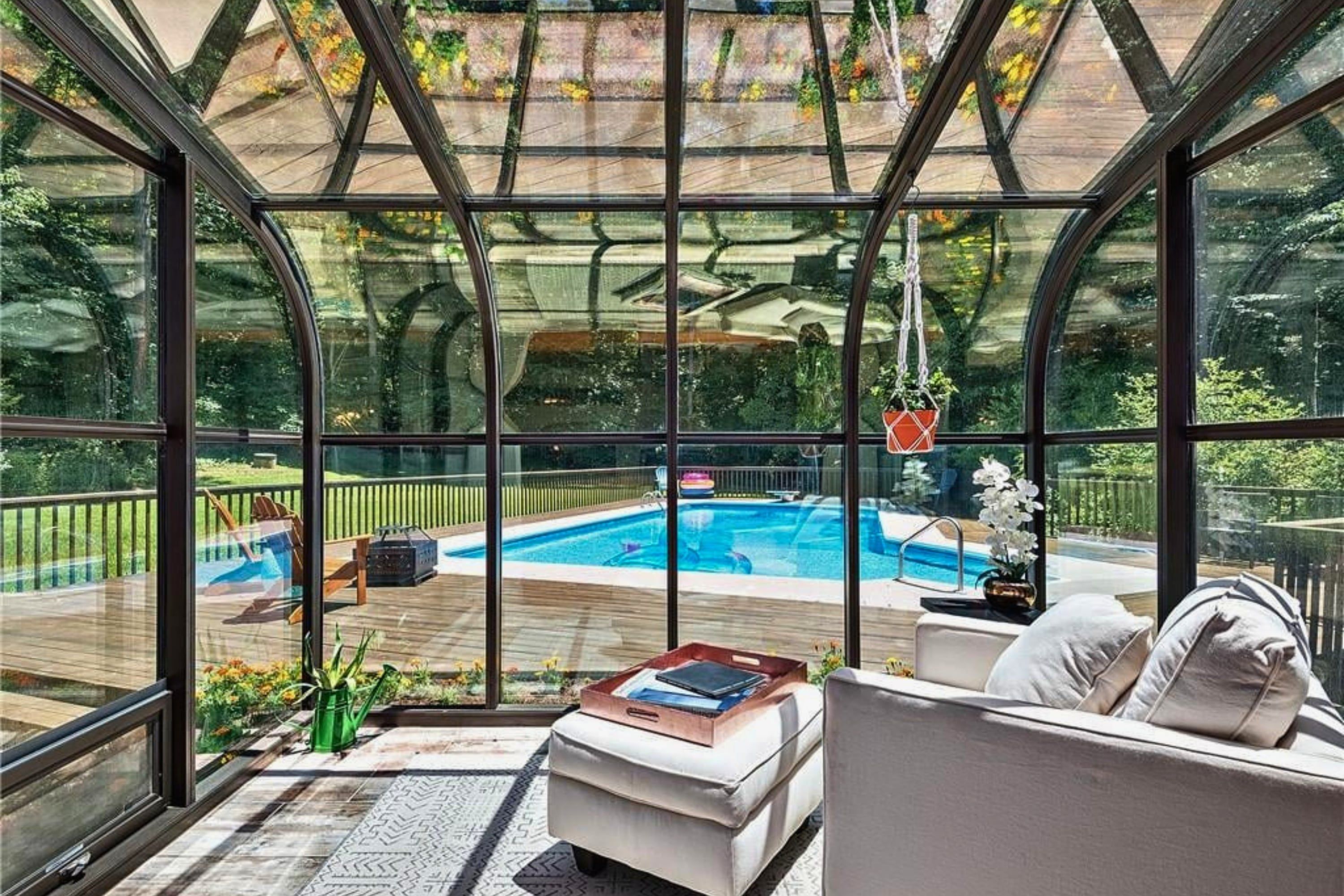 Une véranda avec une piscine, du mobilier d’extérieur et une vue sur le jardin environnant.