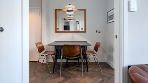Uma sala de jantar com uma mesa retangular, quatro cadeiras e um lustre.