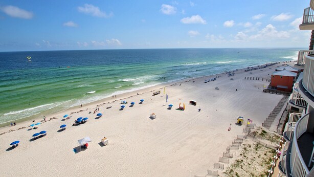 A beach with umbrellas, a lifeguard tower, and a clear view of the ocean. - Beach Front View | Indoor/Outdoor Pools | Hot Tub | Steam Room & Sauna | Sleep 6 (Gulf Shores)