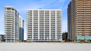A beachfront hotel with multiple floors, balconies, and a modern architectural design. - Beach Front View | Indoor/Outdoor Pools | Hot Tub | Steam Room & Sauna | Sleep 6 (Gulf Shores)
