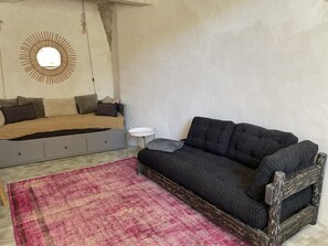 A bedroom with a bed, a sofa, a small round table, and a patterned rug.
