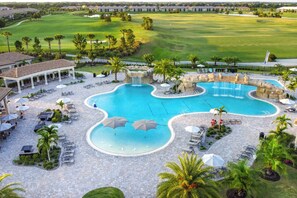 Un complexe hôtelier doté d’une grande piscine, d’un espace extérieur aménagé et d’un terrain de golf en arrière-plan.