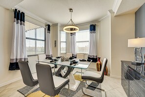 Une salle à manger moderne avec une table en verre, des chaises noires et blanches, et un lustre.