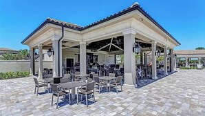 An outdoor patio area with tables and chairs, a covered seating area, and a tiled floor.