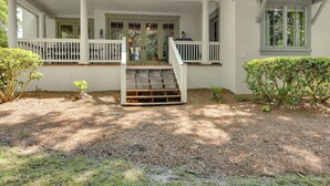 A house with a covered porch, a staircase leading to the entrance, and a well-maintained garden. - 5 Mi to Old Town Bluffton: Cottage w/ Patio (Bluffton)