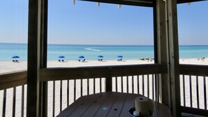 A beach view from a wooden deck with a clear sky.