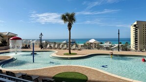 A pool area with a water feature, lounge chairs, and a view of the ocean.