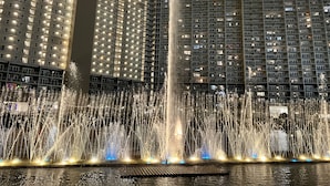 A night view of a hotel with a large water fountain in the foreground and illuminated balconies in the background.