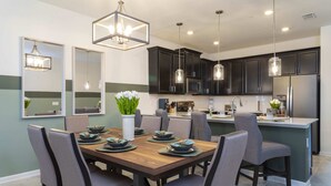 A modern kitchen with dark cabinets, stainless steel appliances, and pendant lighting. - Charming Villa | Themed Rooms | Prime Location (Four Corners)