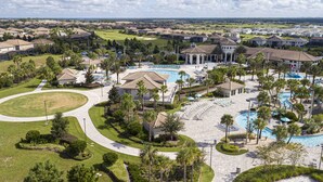 Un complexe hôtelier doté d’une piscine centrale, de plusieurs espaces de détente et d’un terrain de golf en arrière-plan.