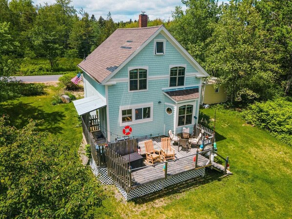 Une maison à deux étages dotée d’une terrasse, entourée d’une végétation luxuriante.