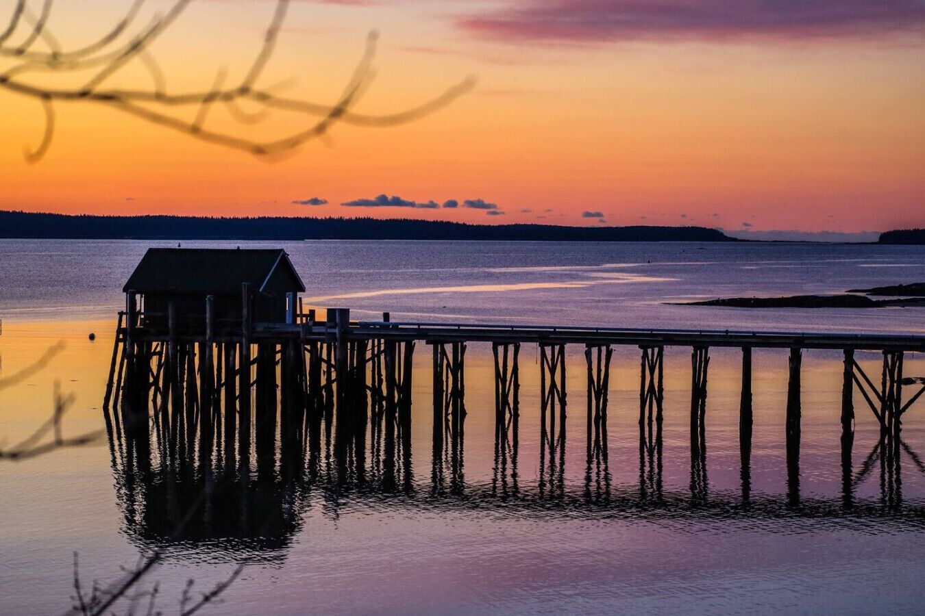 A pier extending into calm water with a small building at the end.