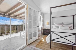 A bedroom with a bed, a nightstand, a lamp, and a view of the outdoors. - Cozy Cottage just 15 Mins North of Downtown Weatherford! (Weatherford)