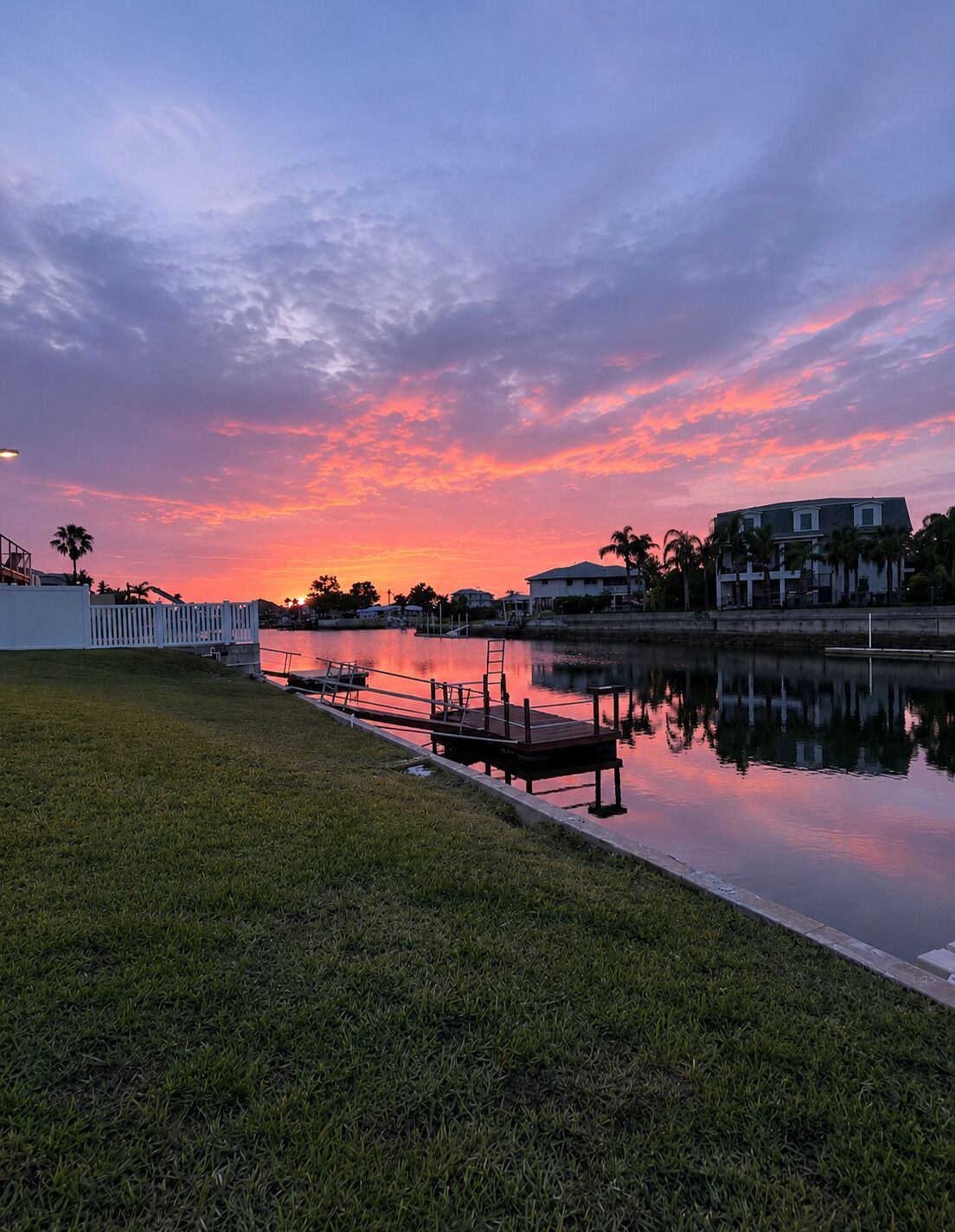 A waterfront property with a dock, grassy area, and buildings in the background.