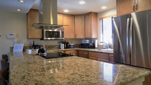 A kitchen with granite countertops, stainless steel appliances, wooden cabinets, and a built-in microwave. - Palm Desert retreat right on the golf course with King en-suite  (Palm Desert)
