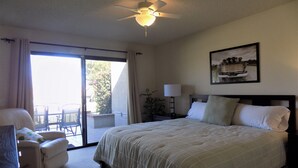 A hotel room with a large bed, a ceiling fan, a window with curtains, a small table with a lamp, and a painting on the wall. - Palm Desert retreat right on the golf course with King en-suite  (Palm Desert)