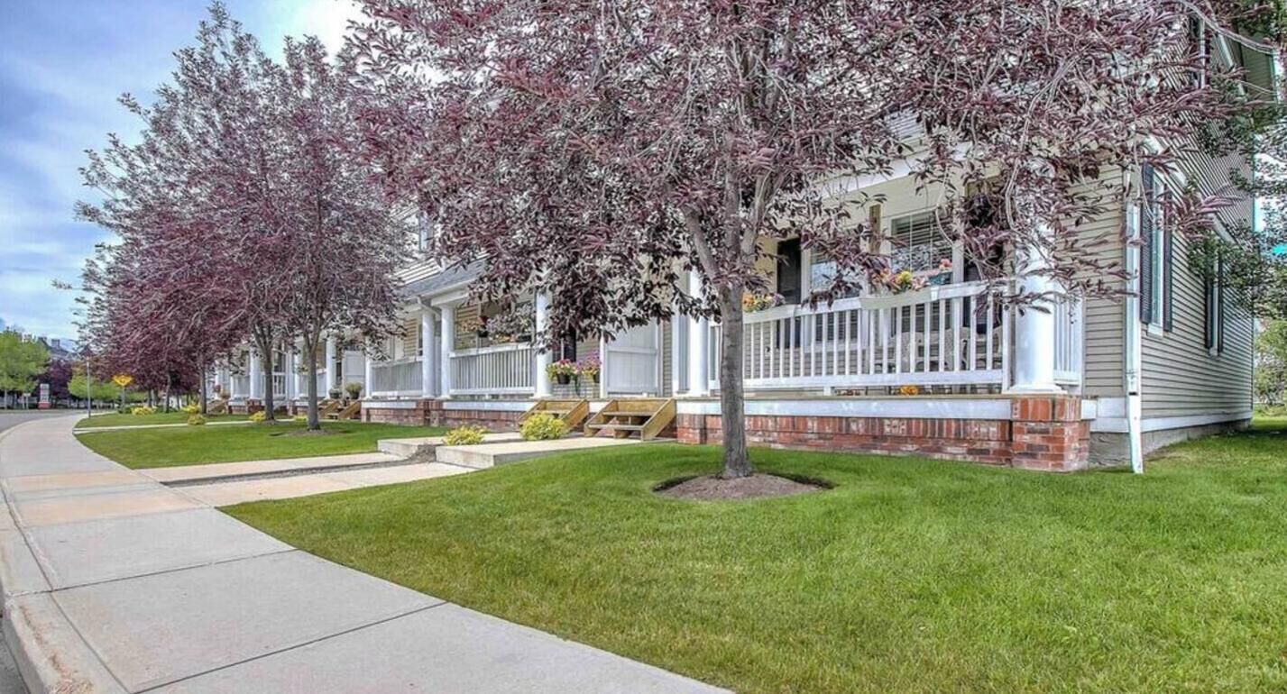 A row of single-family homes with front porches, a sidewalk, and a grassy lawn.