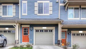A two-story residential building with a garage on the ground floor and a red door. - Enchanted Escape in Northwest Calgary Townhome (Calgary)