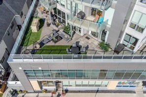Ein modernes Gebäude mit Dachterrasse, Sitzgelegenheiten im Freien und einem kleinen Garten.