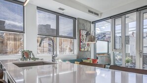 A modern kitchen with a large island, large windows, and a view of the city.