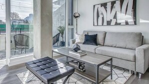 A modern living room with a sofa, a coffee table, and a large window with a view of the city.