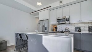 A modern kitchen with a central island, stainless steel appliances, and a bar stool.