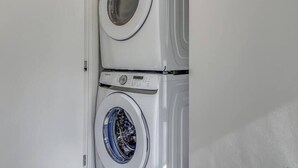 A compact laundry room with two stacked front-loading washing machines.