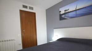 A bedroom with a large bed, a wooden door, a radiator, and a painting of a bridge over water on the wall. - 101-LARESMAN-MAGNIFICENT AND SPACIOUS APARTMENT JUST 2 MINUTES FROM THE BEACH (SALOU)