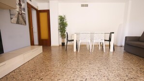 A living room with a dining table and chairs, a sofa, a potted plant, and a door leading to another room. - 101-LARESMAN-MAGNIFICENT AND SPACIOUS APARTMENT JUST 2 MINUTES FROM THE BEACH (SALOU)