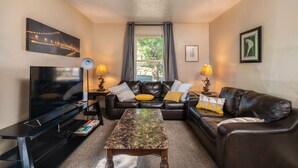 A living room with a TV, leather sofas, a coffee table, and two lamps. - Experience Twin Cites, Spacious, Entire House (Saint Paul)