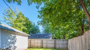 A backyard with a metal table and chairs, a wooden fence, and a shed. - Experience Twin Cites, Spacious, Entire House (Saint Paul)