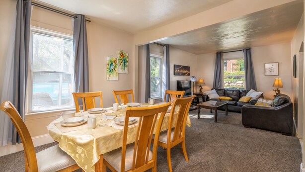 A dining area with a table set for four, a sofa, and a TV in the background. - Experience Twin Cites, Spacious, Entire House (Saint Paul)