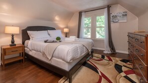 A bedroom with a bed, bedside tables, a dresser, a window with curtains, and a painting on the wall. - Experience Twin Cites, Spacious, Entire House (Saint Paul)