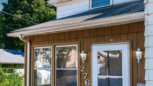 A two-story house with a white door and windows, number 276, and a small porch area with plants. - Experience Twin Cites, Spacious, Entire House (Saint Paul)