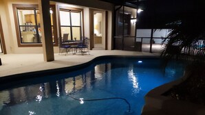 An indoor swimming pool with a clear water surface, surrounded by a covered patio area with a table and chairs. - Cape Coral Paradise: Executive Home, weekly & monthly rates upon request. (Cape Coral)