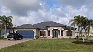A single-story house with a garage, a driveway, and a well-maintained lawn. - Cape Coral Paradise: Executive Home, weekly & monthly rates upon request. (Cape Coral)