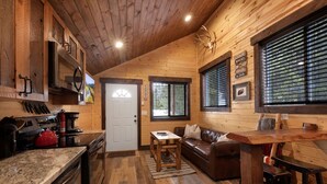 A cozy cabin interior with a wooden interior, a kitchen area, a living room with a sofa, and a dining area. - SUPER CUTE RUSTIC & CLEAN HOME 40 minutes to YNP (Island Park)