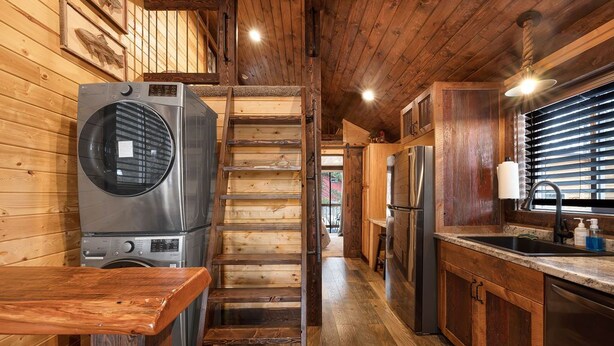 A wooden interior with a washing machine, a wooden staircase, a kitchen area with a refrigerator, and a sink. - SUPER CUTE RUSTIC & CLEAN HOME 40 minutes to YNP (Island Park)