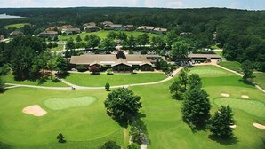 A golf course with a clubhouse and residential buildings in the background.