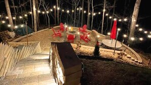 A stone staircase leading to a patio area with a fire pit and red chairs.