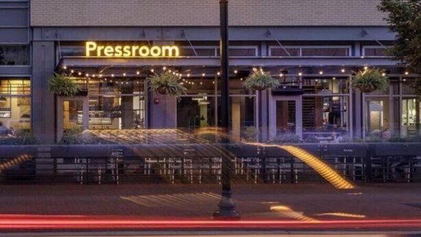 A building with a sign reading "Pressroom" and a street lamp in front.