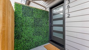 Une maison moderne avec un mur végétal et une porte grise.
