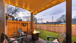 Un patio couvert avec un foyer, des sièges d’extérieur et une vue sur le jardin.